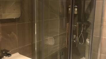 A modern bathroom with a glass-enclosed shower, a white sink, and a mirror above the sink.