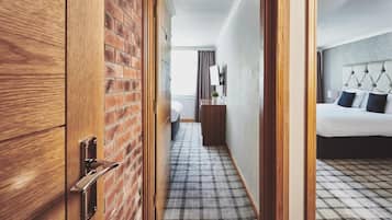 A hotel room with a checkered floor, a bed with a tufted headboard, a bedside table, and a mirror on the wall.