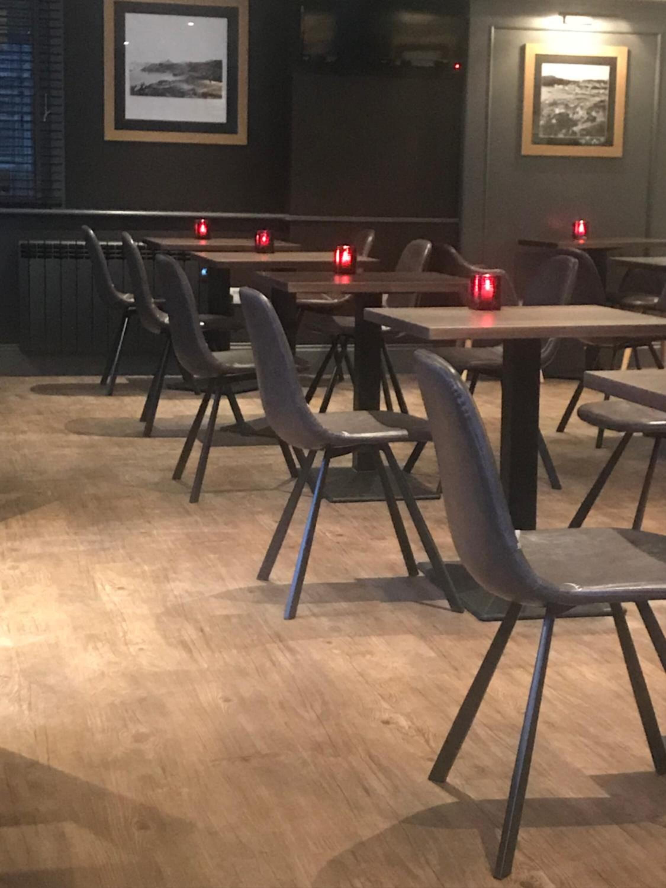 A restaurant interior with wooden flooring, metal chairs, and tables.
