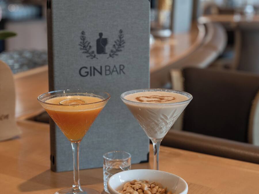 A bar area with two martini glasses and a bowl of nuts on a wooden table.
