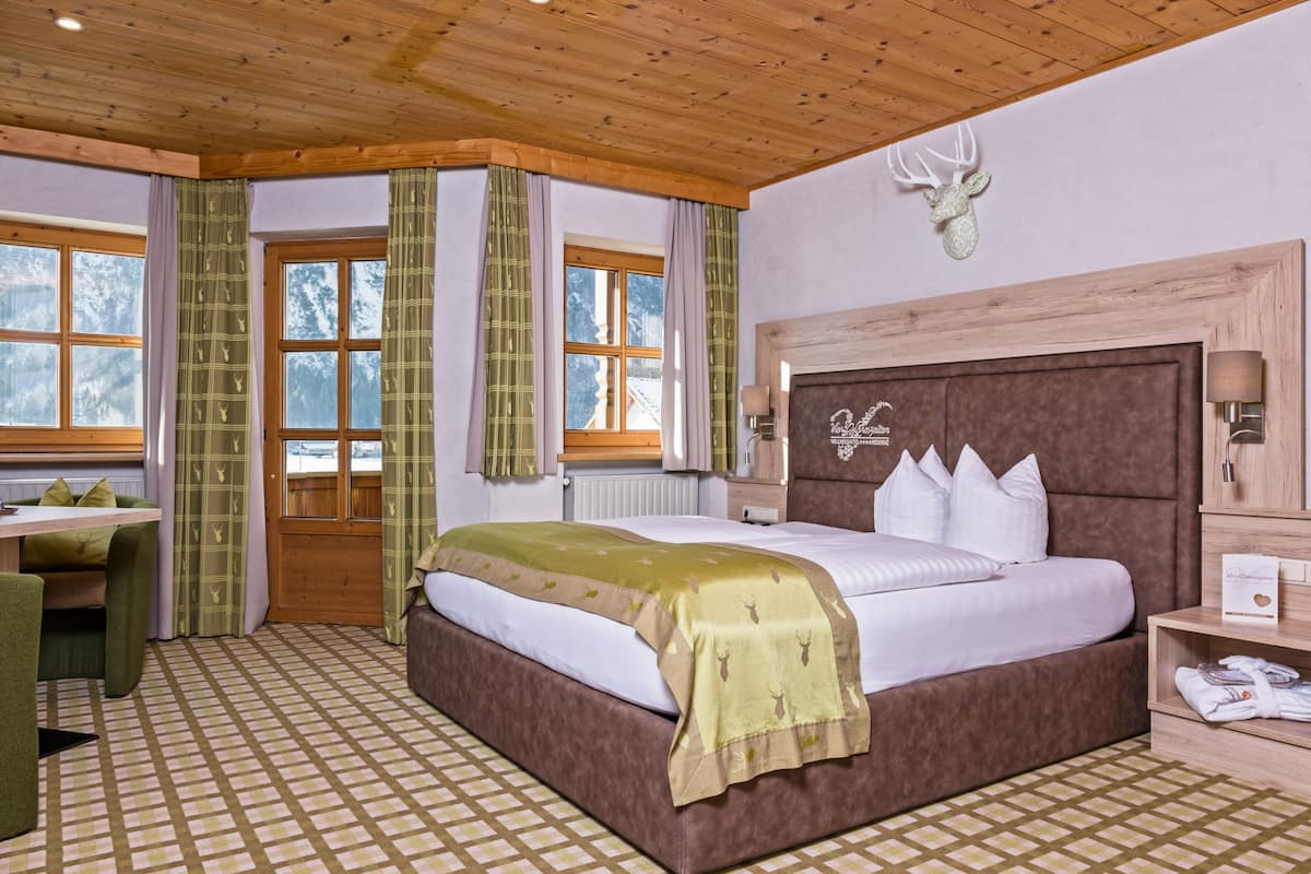 Ein Schlafzimmer mit einem großen Bett, einem hölzernen Kopfteil, einer Dekoration mit Hirschgeweih und einem Schachbrettfußboden.