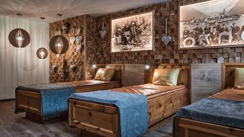 Una habitación con tres camas de madera, un panel de madera decorado con un cuadro y adornos colgantes con forma de corazón.