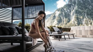 Ein moderner Außenbereich zum Sitzen mit einer Couch und Stühlen, einem überdachten Sitzbereich und Blick auf die Berge.
