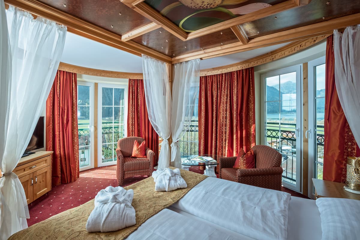 Ein Hotelzimmer mit Bett, zwei Stühlen, einem Fernseher und einem Balkon mit Blick.