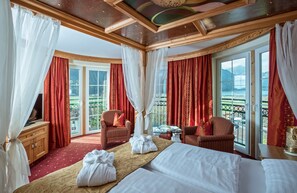 Ein Hotelzimmer mit Bett, zwei Stühlen, einem Fernseher und einem Balkon mit Blick.