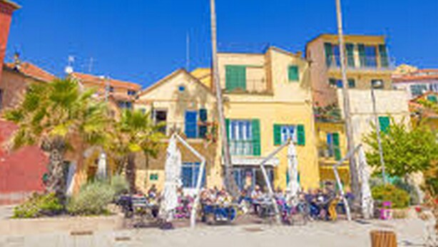 Une ville côtière aux bâtiments aux couleurs vives, bordée de palmiers, sous un ciel bleu azur.