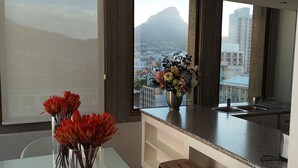 Eine moderne Küche mit großem Fenster, einer Blumenvase und Blick auf eine Stadtlandschaft.