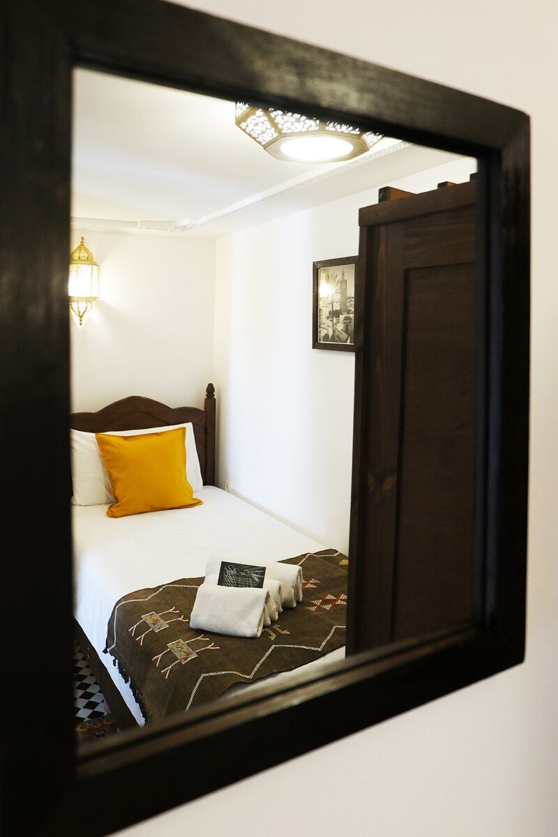 A hotel room with a bed, a nightstand, a lamp, and a framed picture on the wall.