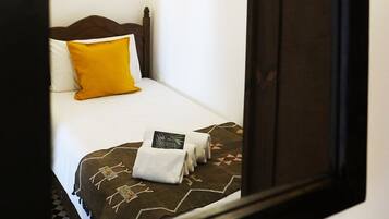 A hotel room with a bed, a nightstand, a lamp, and a framed picture on the wall.