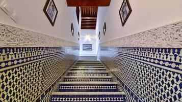 Un escalier orné de motifs complexes en carreaux bleus et blancs, menant à un étage supérieur.