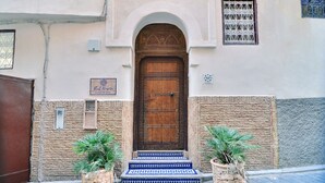 Una casa tradicional marroquí con una puerta de madera, un pequeño balcón y un cartel.