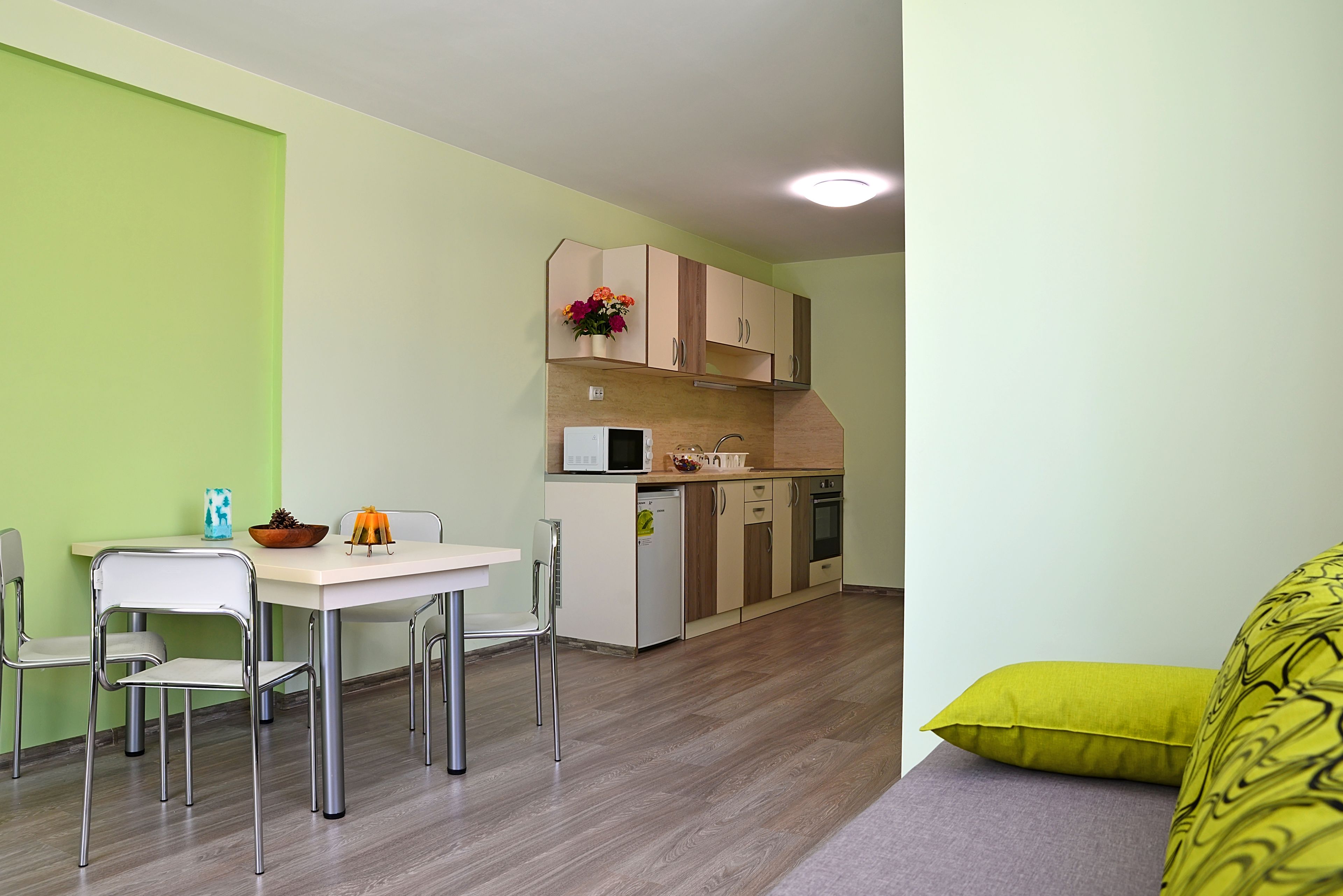 A compact kitchen with a dining area, featuring a white table, chairs, and a microwave.
