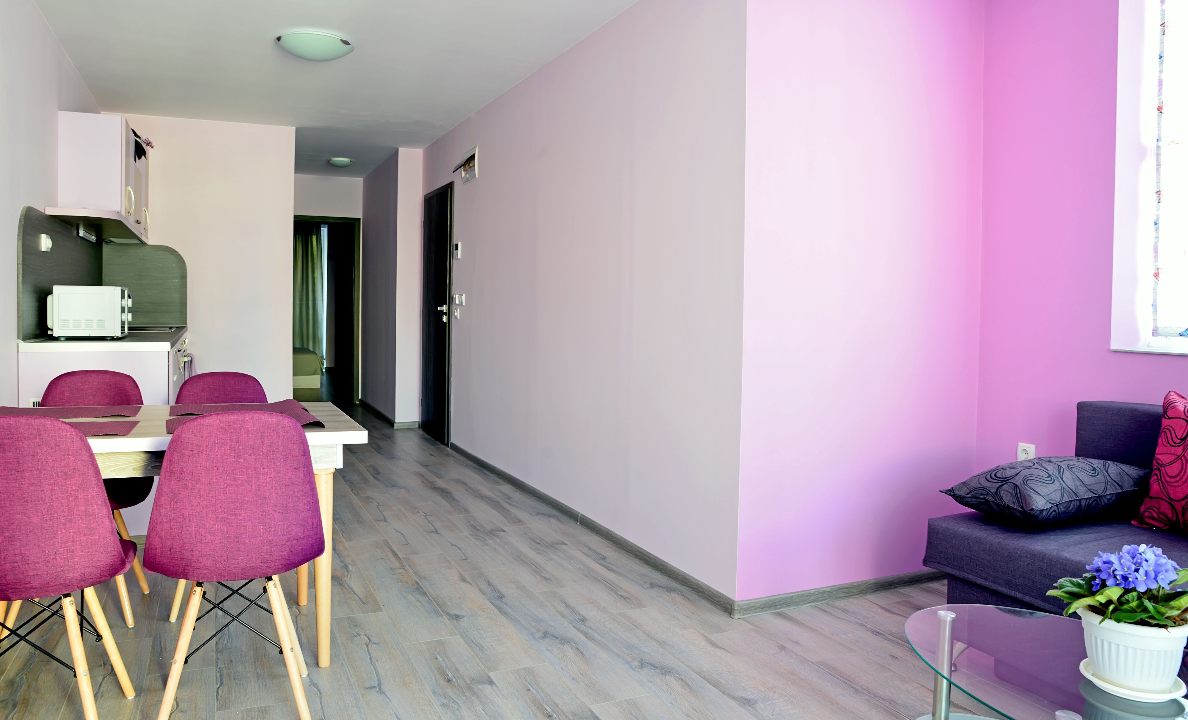 Una sala de estar moderna con comedor, que incluye un sofá, sillas, una mesa de centro de vidrio y una pequeña mesa con sillas.