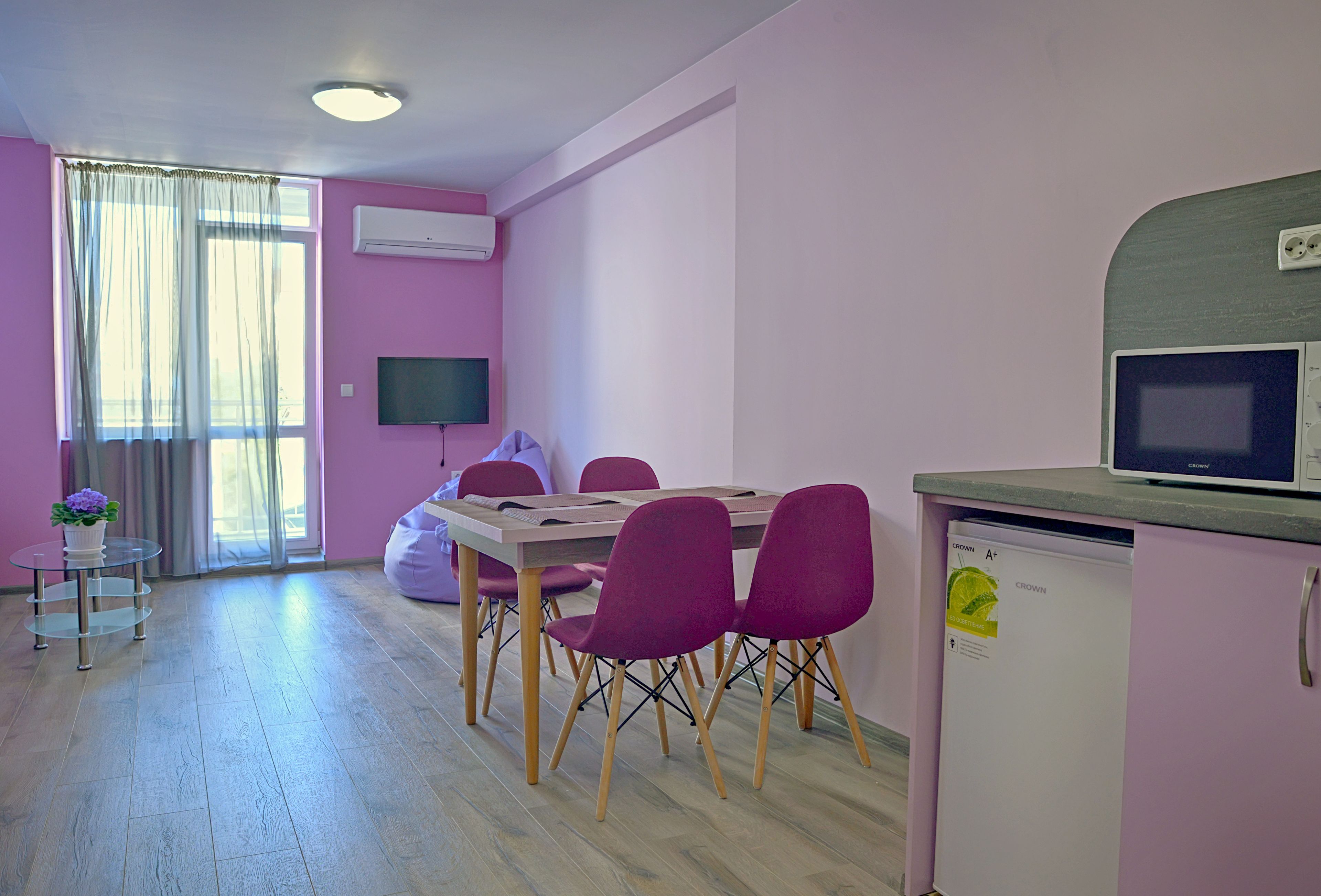A modern kitchen with a dining area, a refrigerator, and a television.
