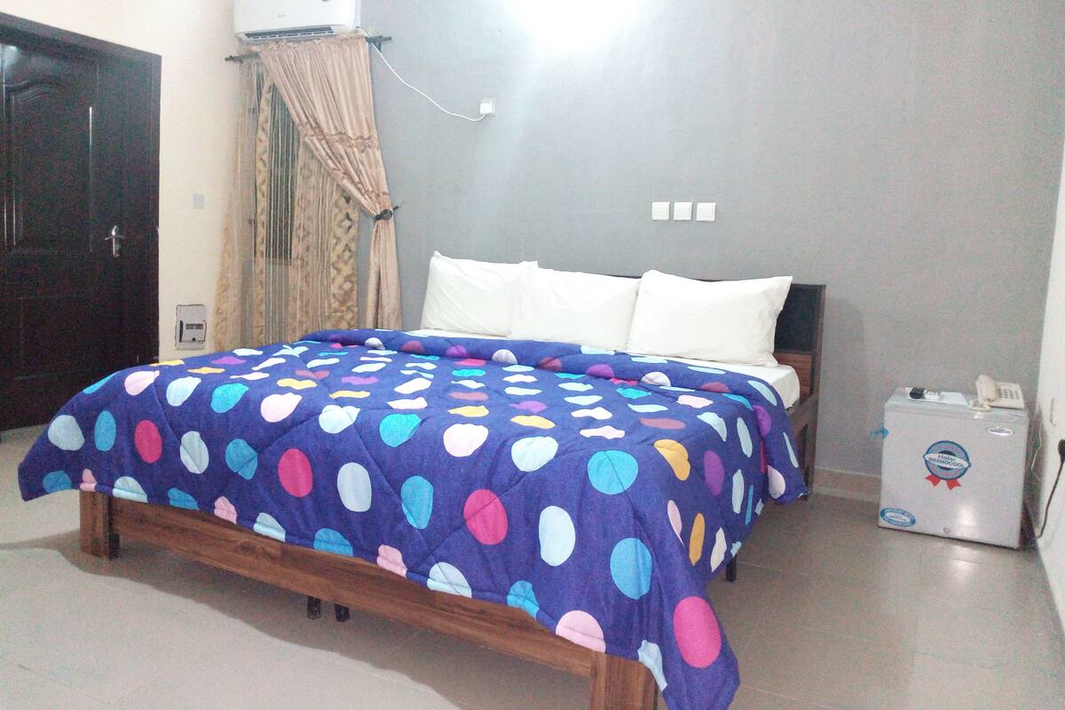 A bedroom with a bed, a bedside table, a heater, and a door.