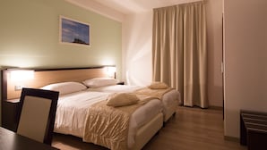 A hotel room with a double bed, a nightstand, a desk, and a large window with curtains. - Albergo Ristorante Bismantova (Castelnovo ne' Monti)