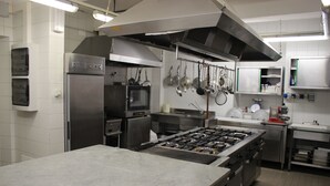 A commercial kitchen with stainless steel appliances, a large island, and hanging pots and pans. - Albergo Ristorante Bismantova (Castelnovo ne' Monti)