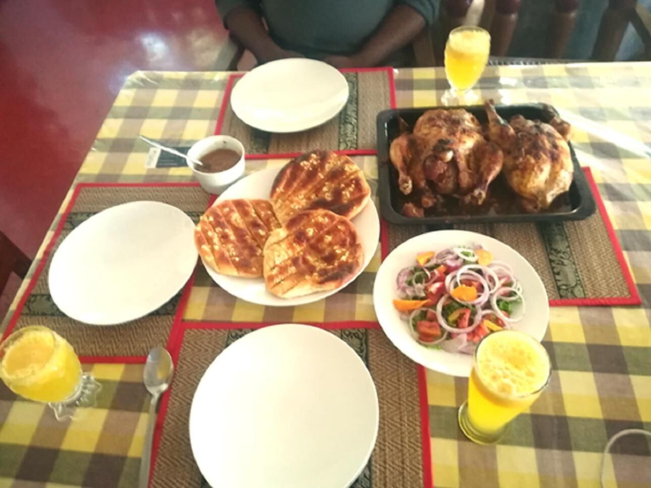 A table set with plates, a tray of roasted chicken, a salad, and drinks.