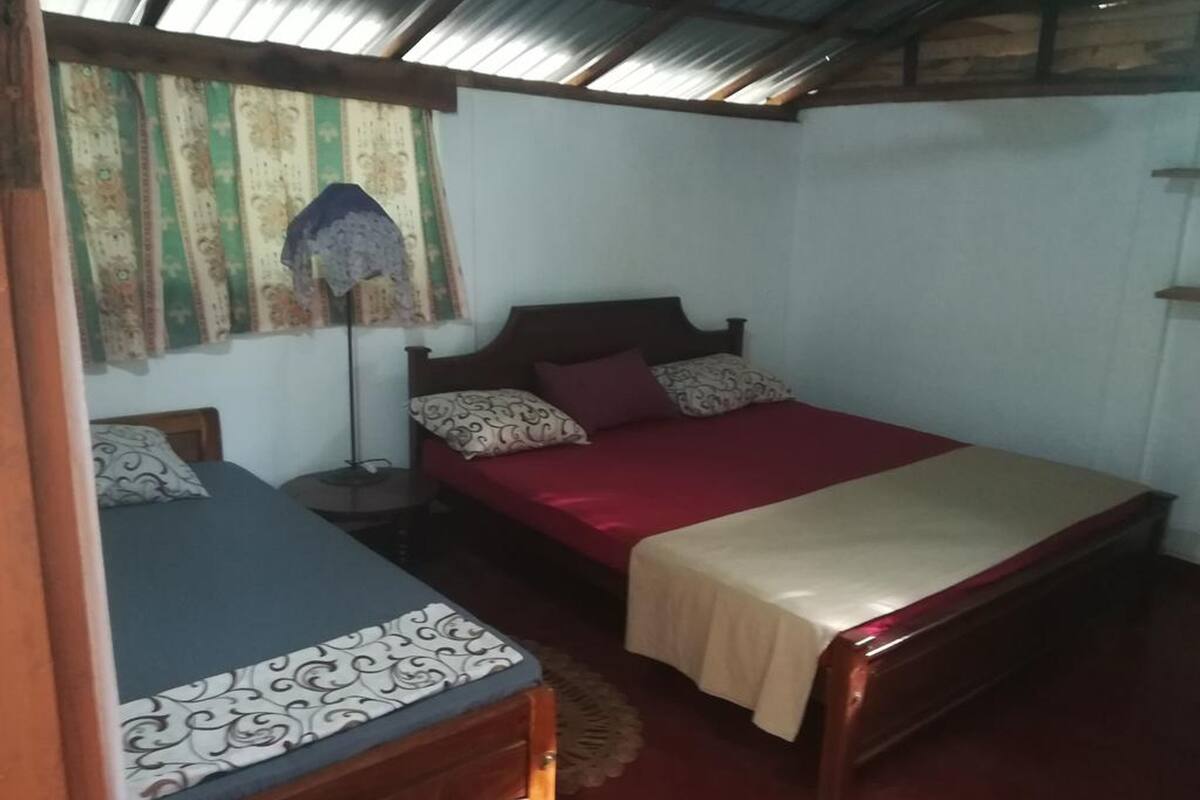 Une chambre avec deux lits, une table de chevet, une lampe et un rideau à motifs.