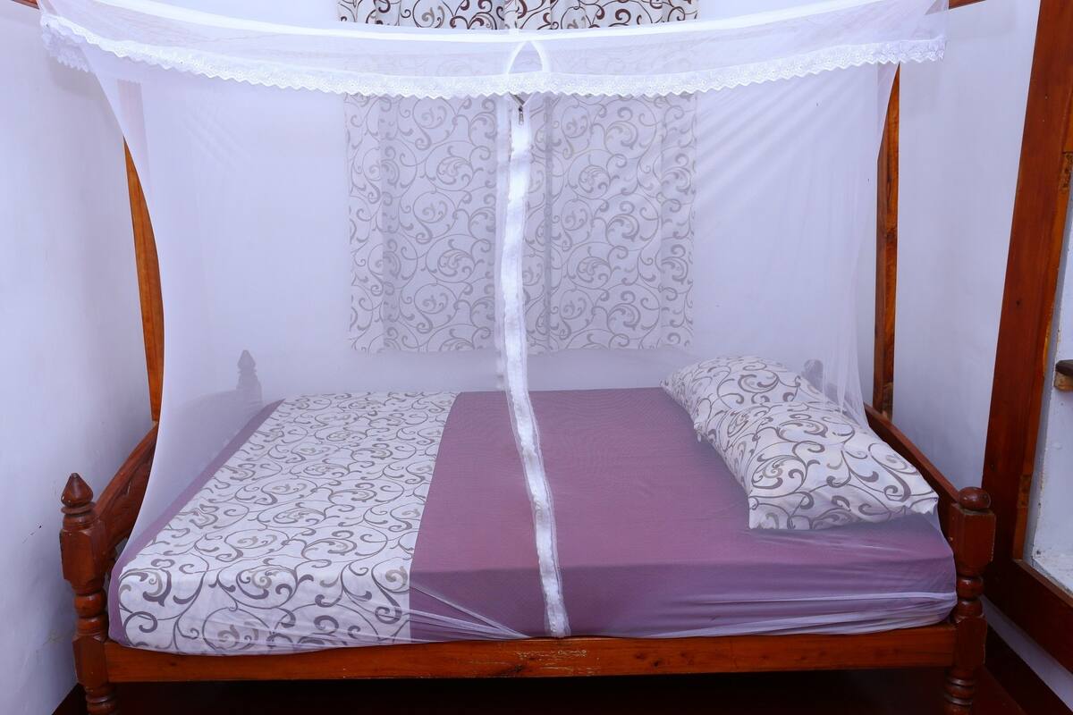 Un lit simple avec un baldaquin, une couvre-lit à motifs et des coussins assortis.