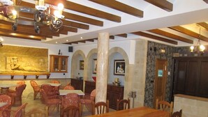 Un comedor con una larga mesa de madera y sillas, un pilar grande y un mural en la pared.