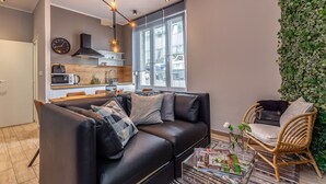 A modern living room with a black leather sofa, a wicker chair, and a dining area with a wooden table and chairs. - Number 1 Apartments Rijeka (Rijeka)