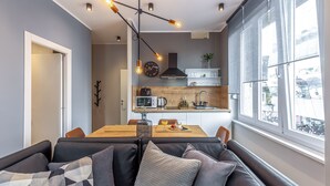 A modern kitchen with a dining area, a sofa with cushions, and a large window with a view. - Number 1 Apartments Rijeka (Rijeka)