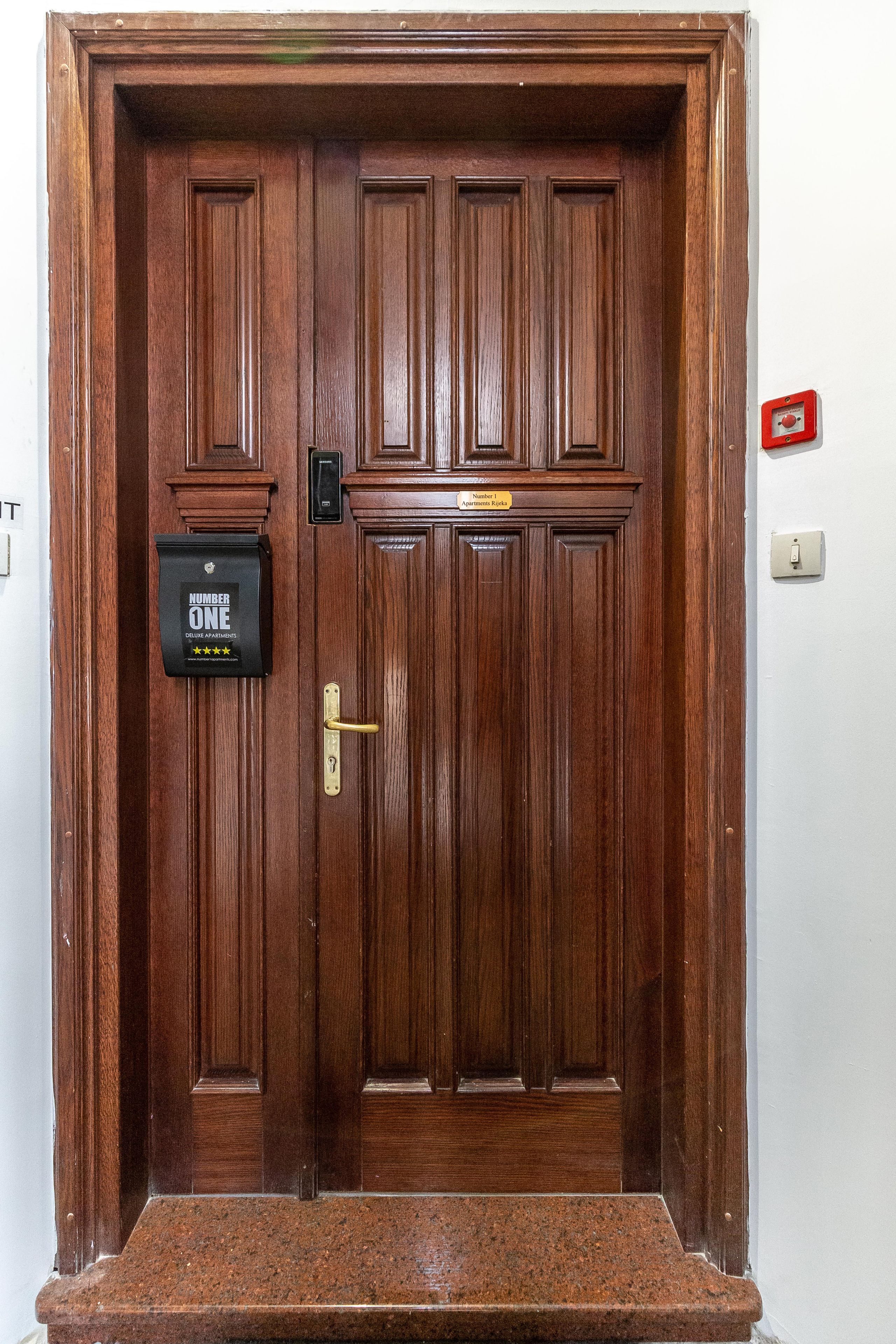 A wooden double door with a mailbox labeled "Number One" and a doorbell.