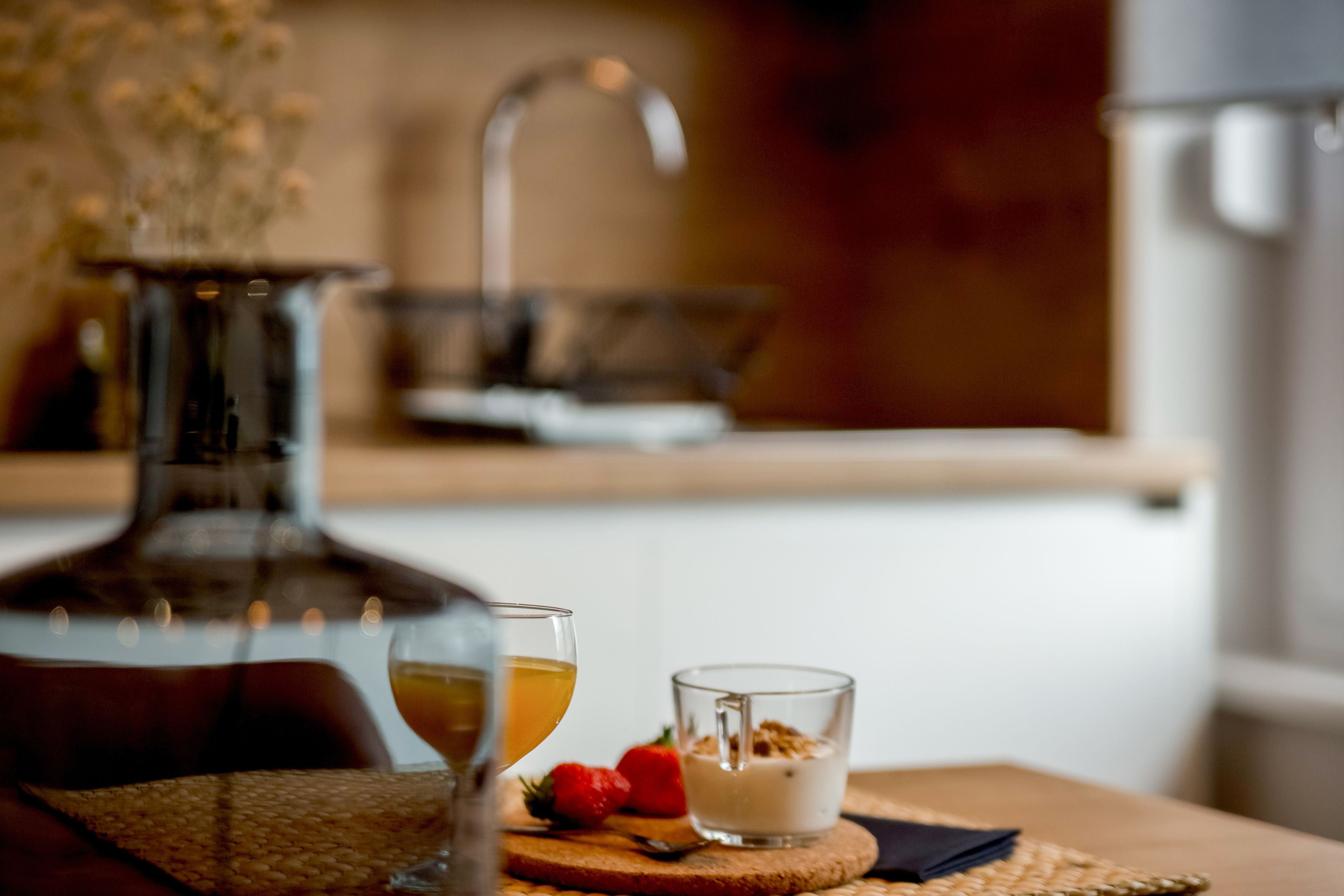 A dining table with a glass of wine, a glass of water, and a small dessert on a woven placemat.
