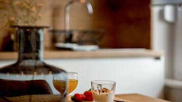 A dining table with a glass of wine, a glass of water, and a small dessert on a woven placemat.