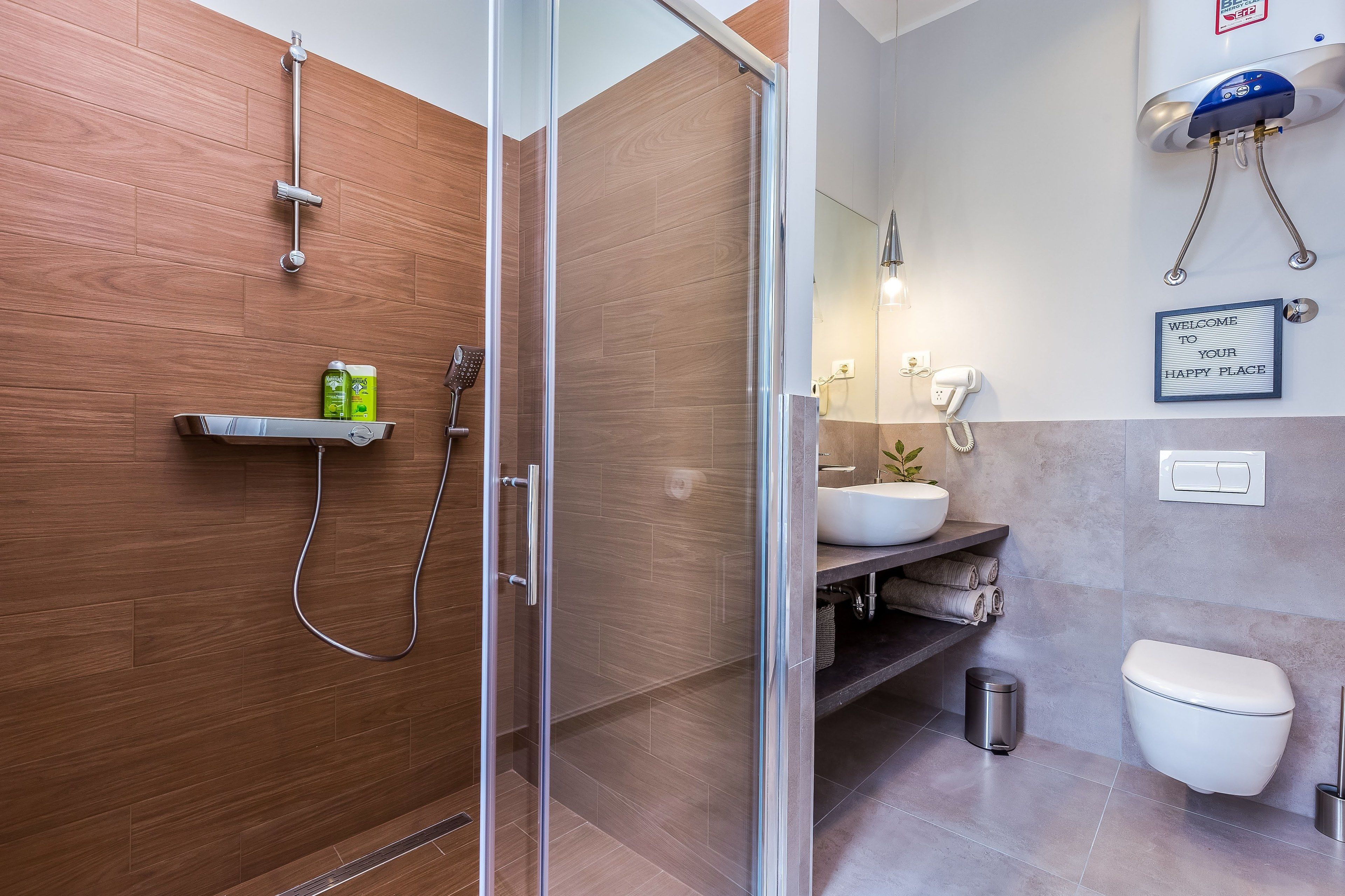 Ein modernes Badezimmer mit Duschkabine aus Glas, einer Holzvertäfelung, einem Waschbecken mit Spiegel und einer Toilette.