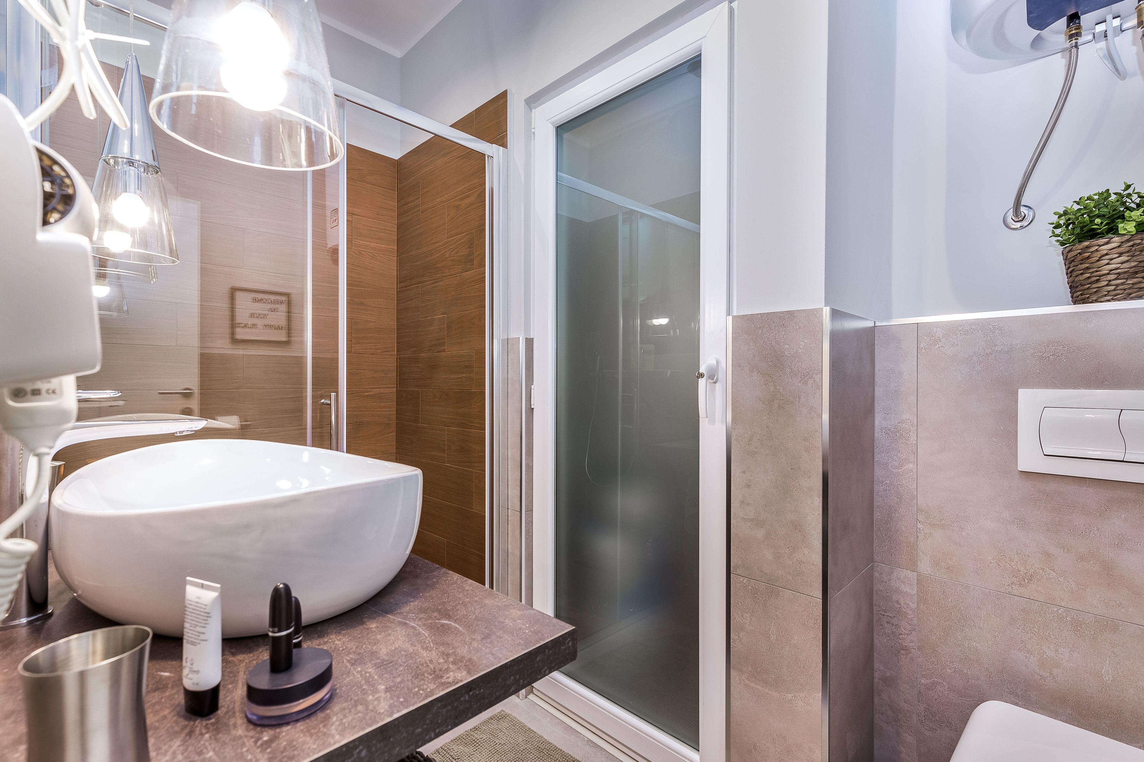 Ein modernes Badezimmer mit einem großen, weißen Waschbecken, einer Duschkabine aus Glas und einer Marmorarbeitsplatte.