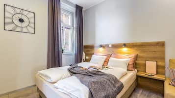 Een net opgemaakt bed met een deken, kussens en een ingelijst beeld op een nachtkastje.
