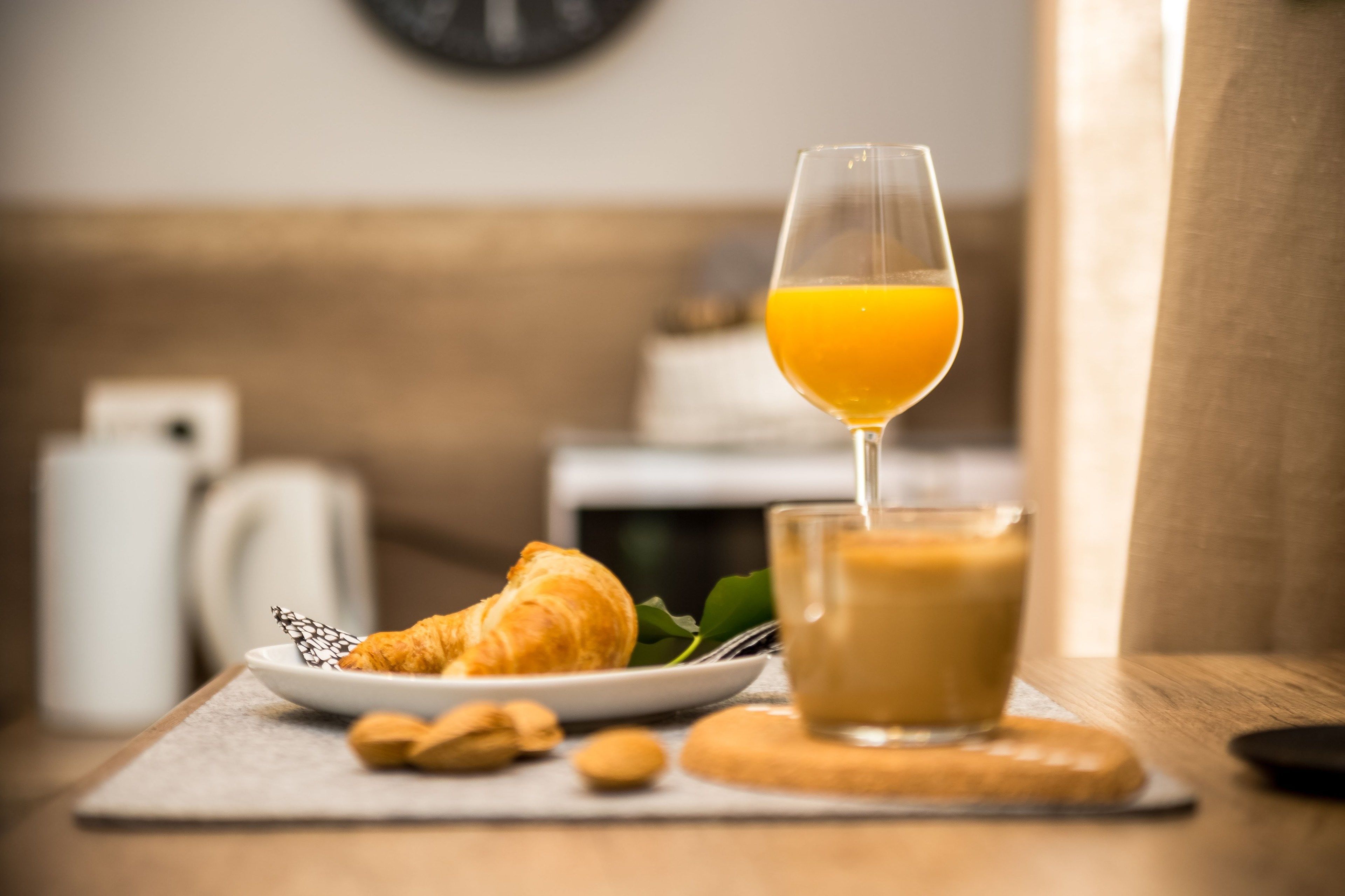 Une table mise pour le petit-déjeuner, avec un croissant, un verre de jus d’orange et une tasse de café.