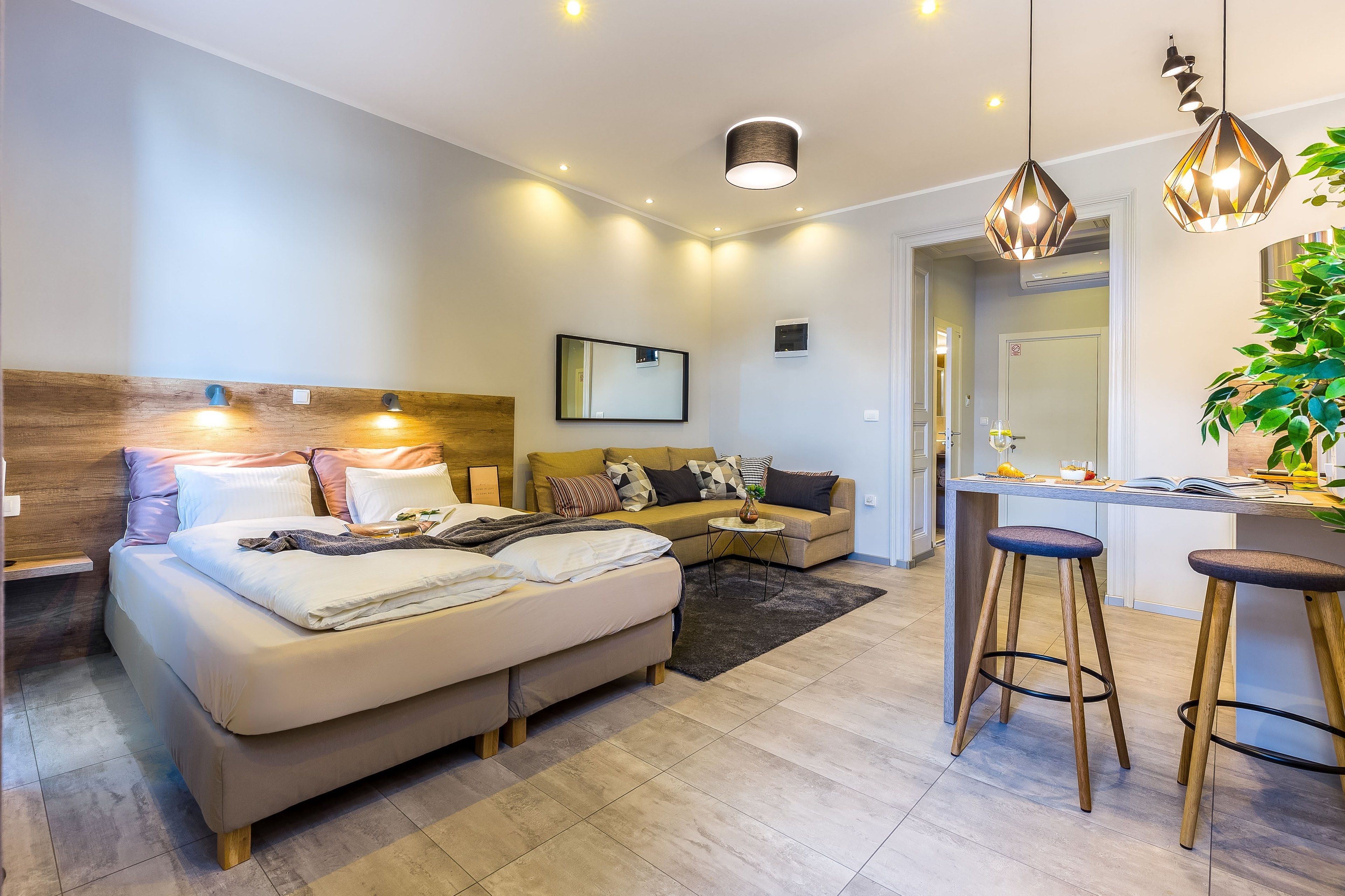 Ett modernt hotellrum med en säng, en soffa, ett litet bord och en barhörna.