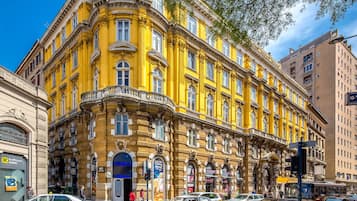 Un edificio histórico amarillo con varias fachadas comerciales, incluyendo un banco y una tienda.