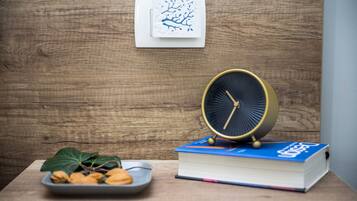 A wooden table with a book, a clock, and a plate of nuts.