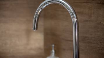 A chrome faucet with a curved design, set against a wooden background.