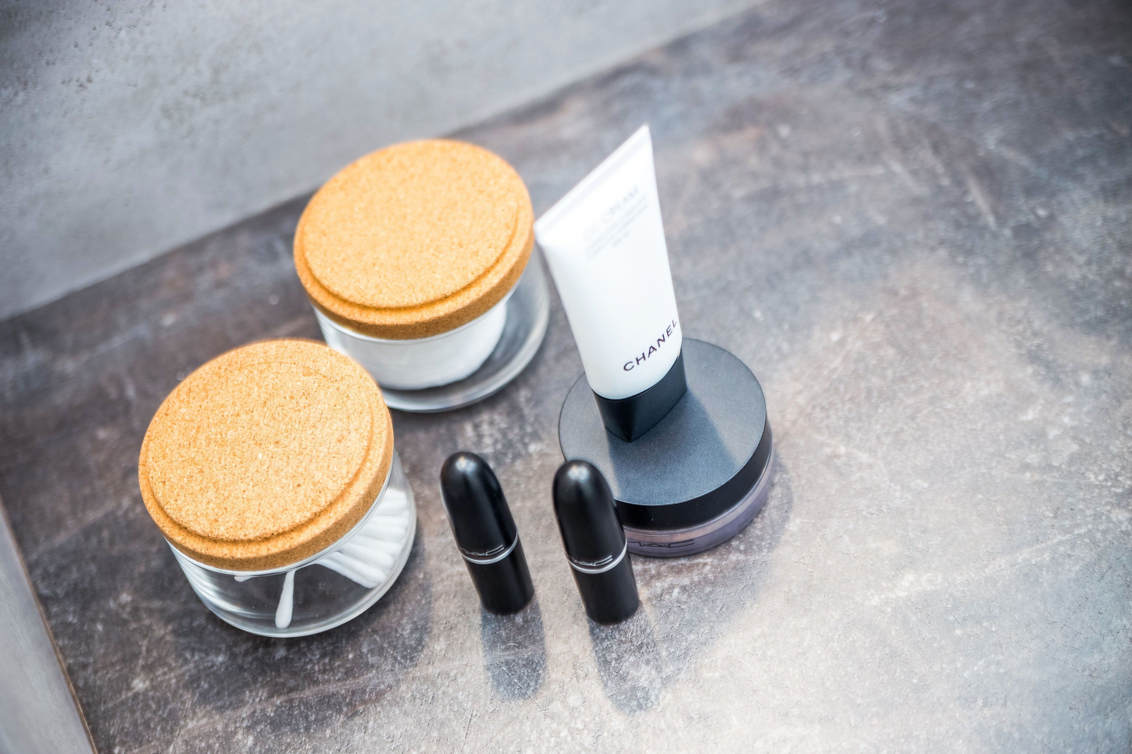Una exhibición de productos cosméticos que incluye un tubo con la etiqueta "CHANEL" y dos recipientes cilíndricos.