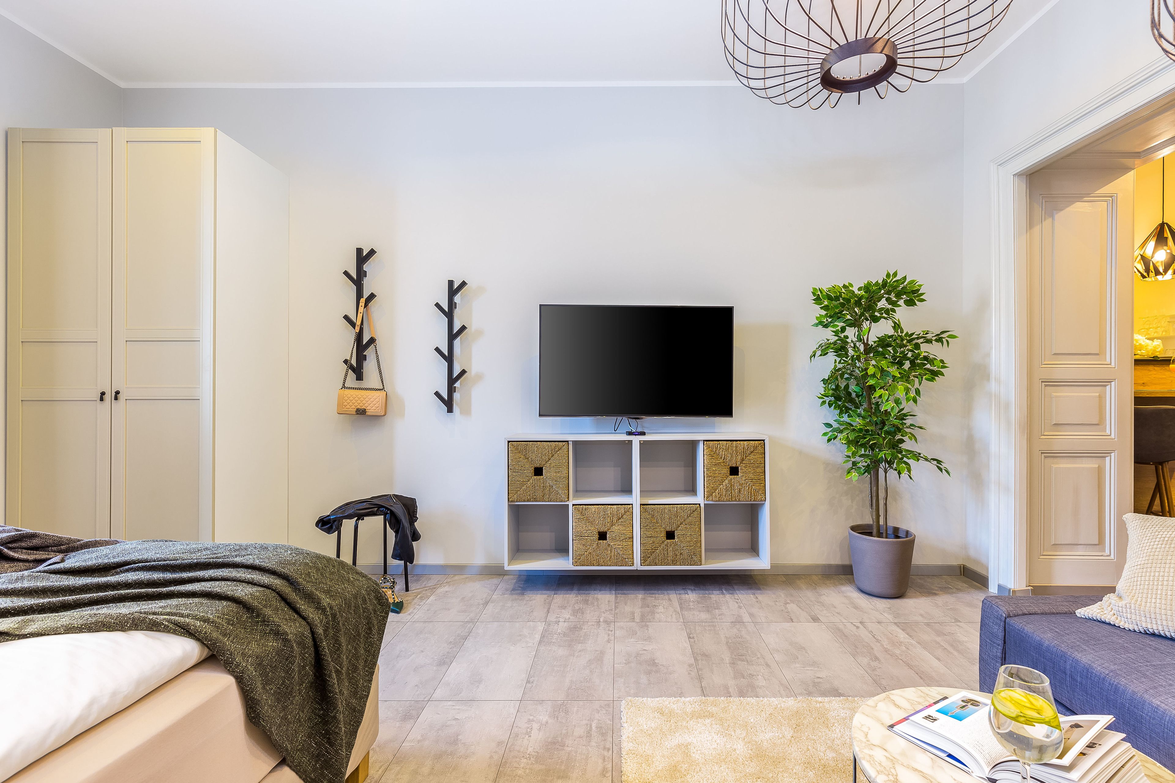 Un salon moderne avec un téléviseur à écran plat, une plante en pot et un canapé.
