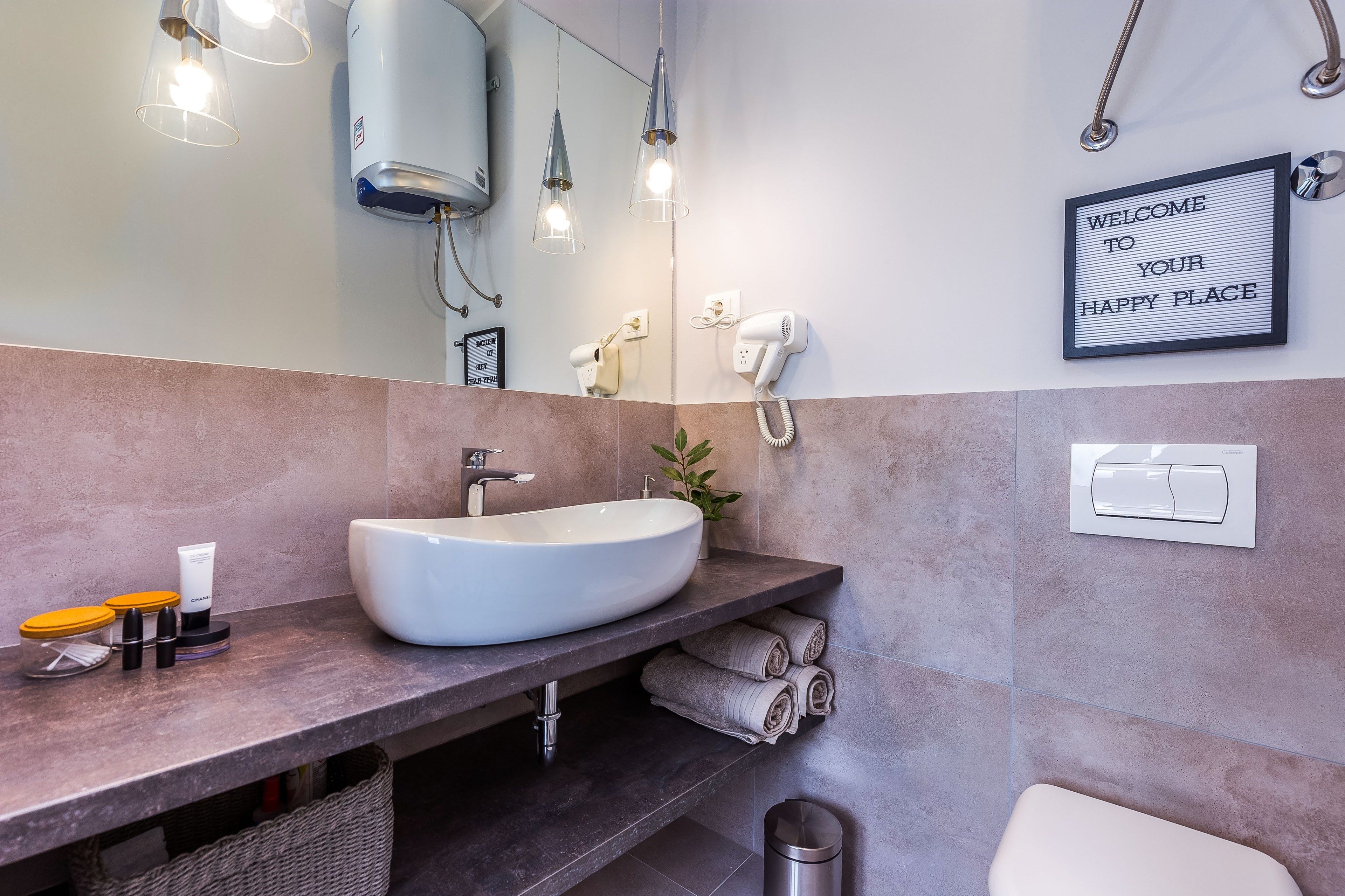 A modern bathroom with a large white sink, a hairdryer, and a towel rack.