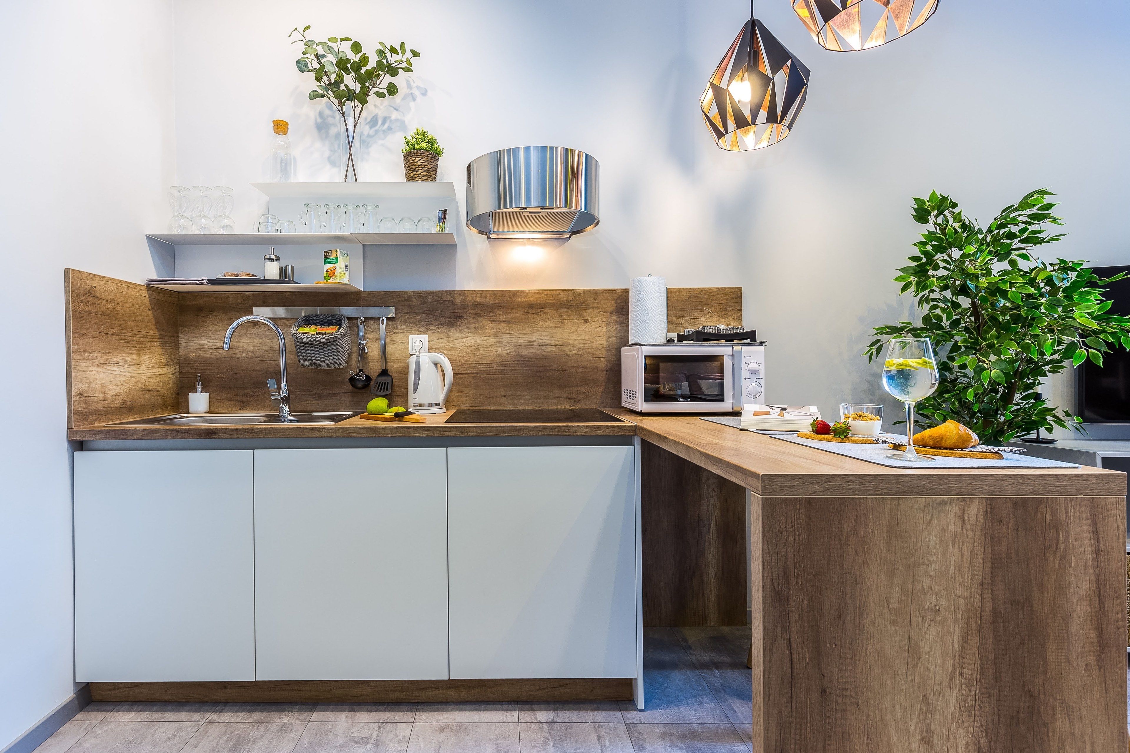 A modern kitchen with a wooden countertop, white cabinets, a microwave, and a sink.