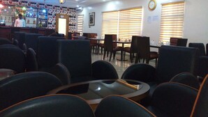 A restaurant with a bar area, seating arrangements, and a clock on the wall. - Bana Hotel & Suites (Lagos)