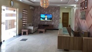 A hotel lobby with a reception desk, seating area, and a television mounted on the wall. - Bana Hotel & Suites (Lagos)