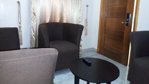 A room with a wooden door, a curtain, and two armchairs. - Bana Hotel & Suites (Lagos)
