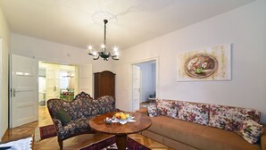 A living room with a round wooden table, floral sofas, and a chandelier. - Apartment Tatjana (Zagreb)