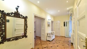 A hallway with a geometric patterned floor, a large ornate mirror, and a white bench with floral upholstery. - Apartment Tatjana (Zagreb)