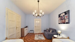 A bedroom with two beds, a sofa, a desk, a chandelier, and a painting on the wall. - Apartment Tatjana (Zagreb)