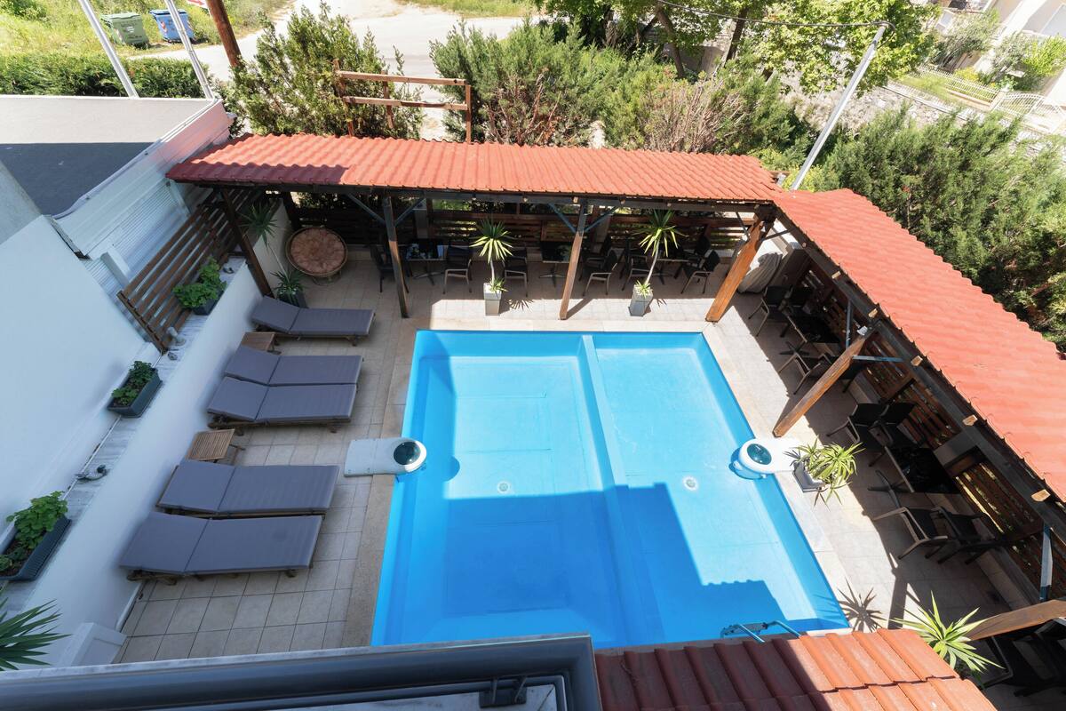 Ein Pool auf dem Dach mit Liegestühlen, einer überdachten Lounge und Blumentöpfen.