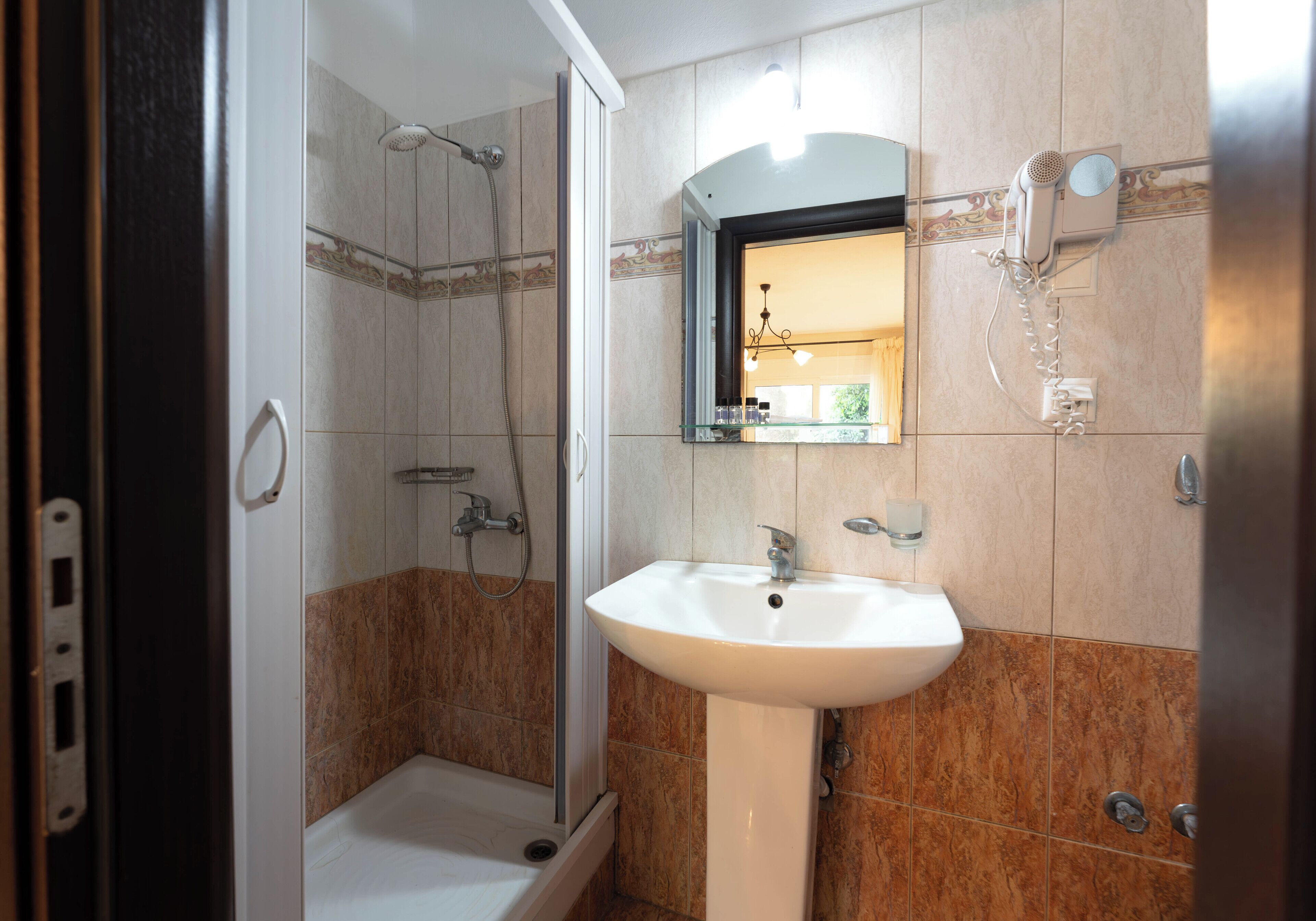 Un baño con ducha, lavabo y espejo.